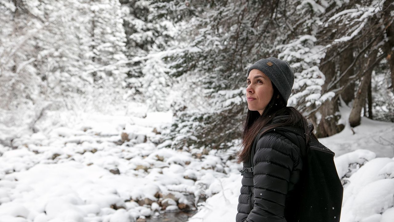 Een vrouw wandelt door een besneeuwd bos