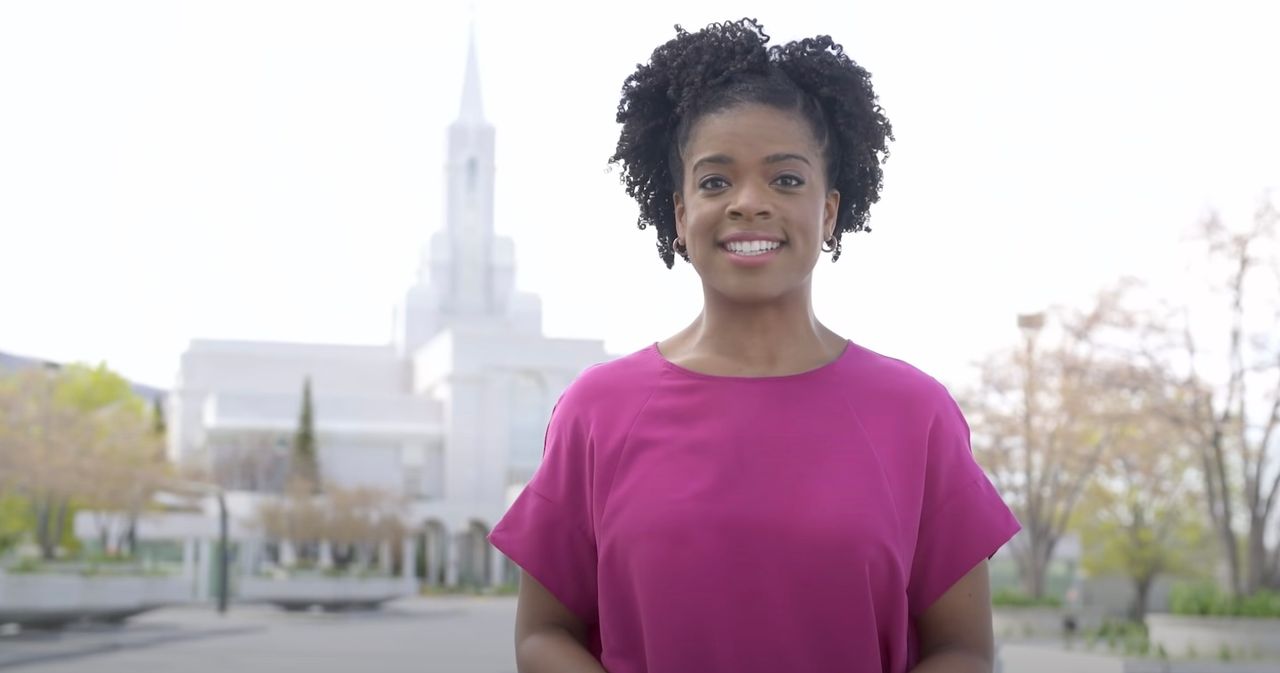 Een vrouw staat in de lente bij een tempel en legt het doel van de doop voor de doden uit