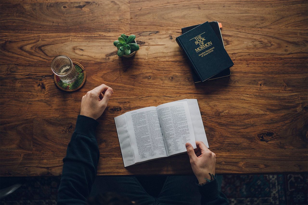 Een man bestudeert de Bijbel en het Boek van Mormon aan de keukentafel