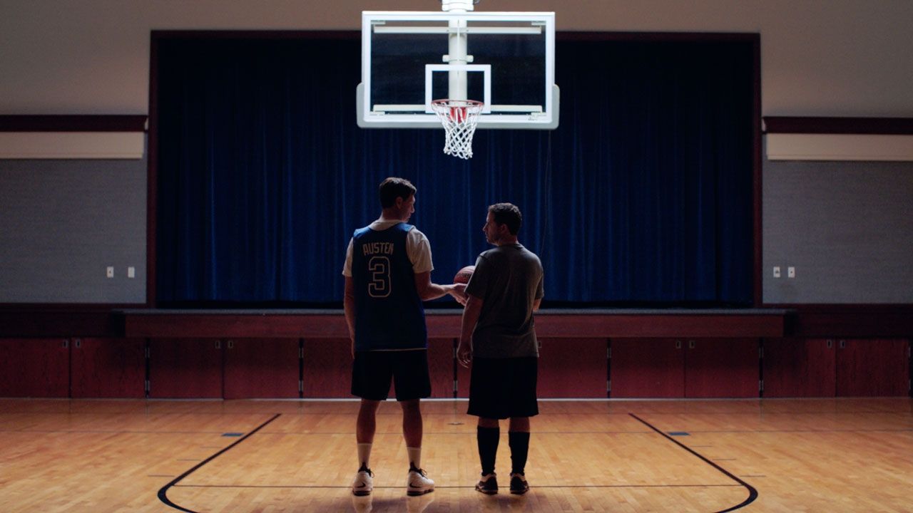 Twee mannen staan naast elkaar onder een basketbalring