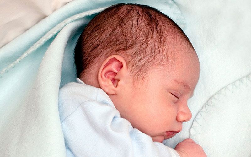 Een slapende pasgeboren baby in een dekentje gewikkeld