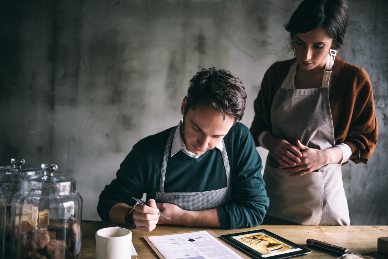 Een echtpaar neemt aan tafel een kookrecept door